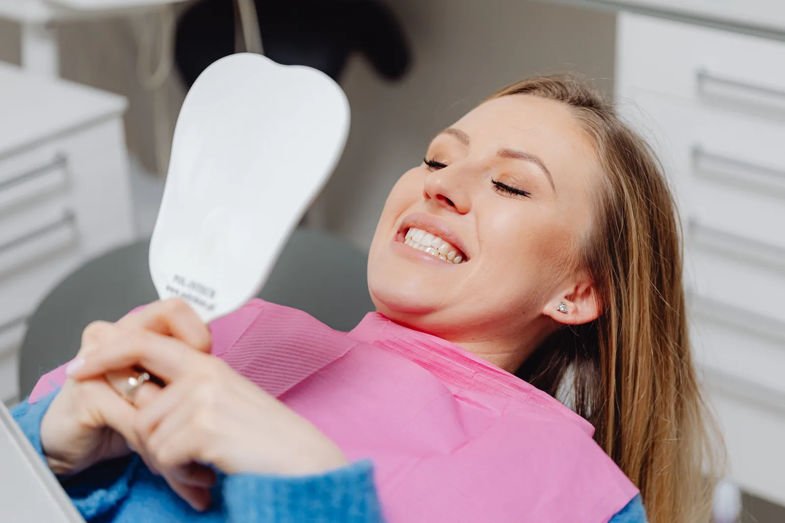 Patient checking her smile in the mirror, shown while covering All-on-6 Implants in Toronto