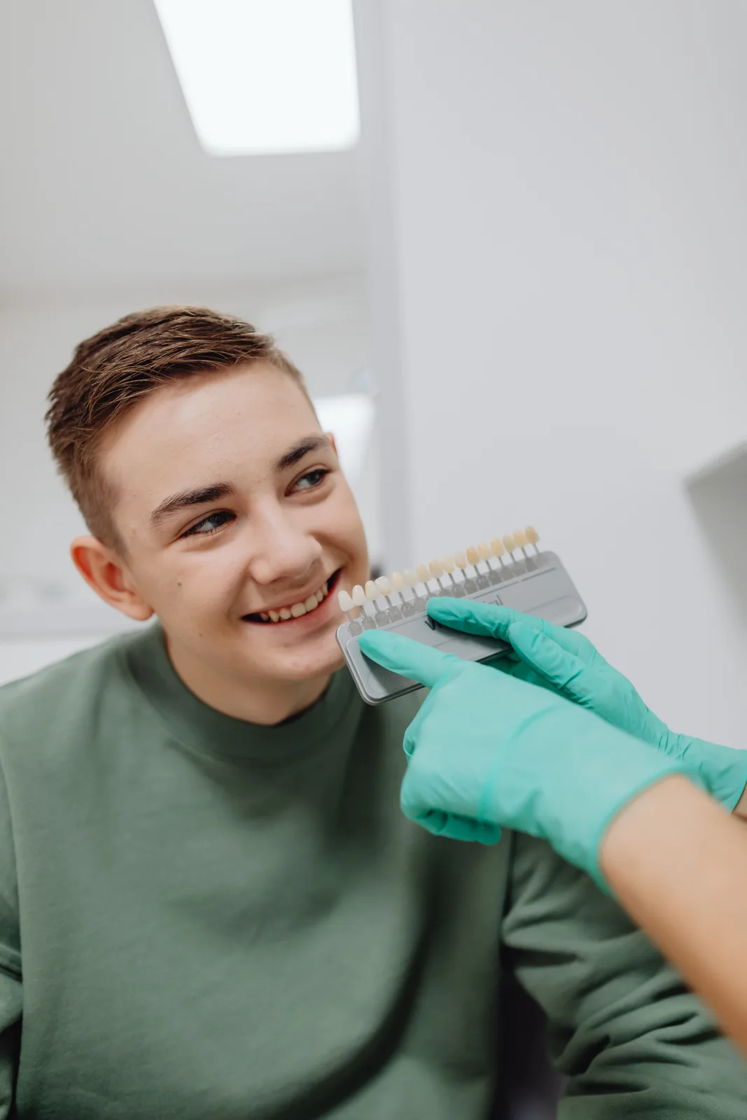 Shade guide held beside the patient smile, shown while covering Dentures Vs Implants in Toronto